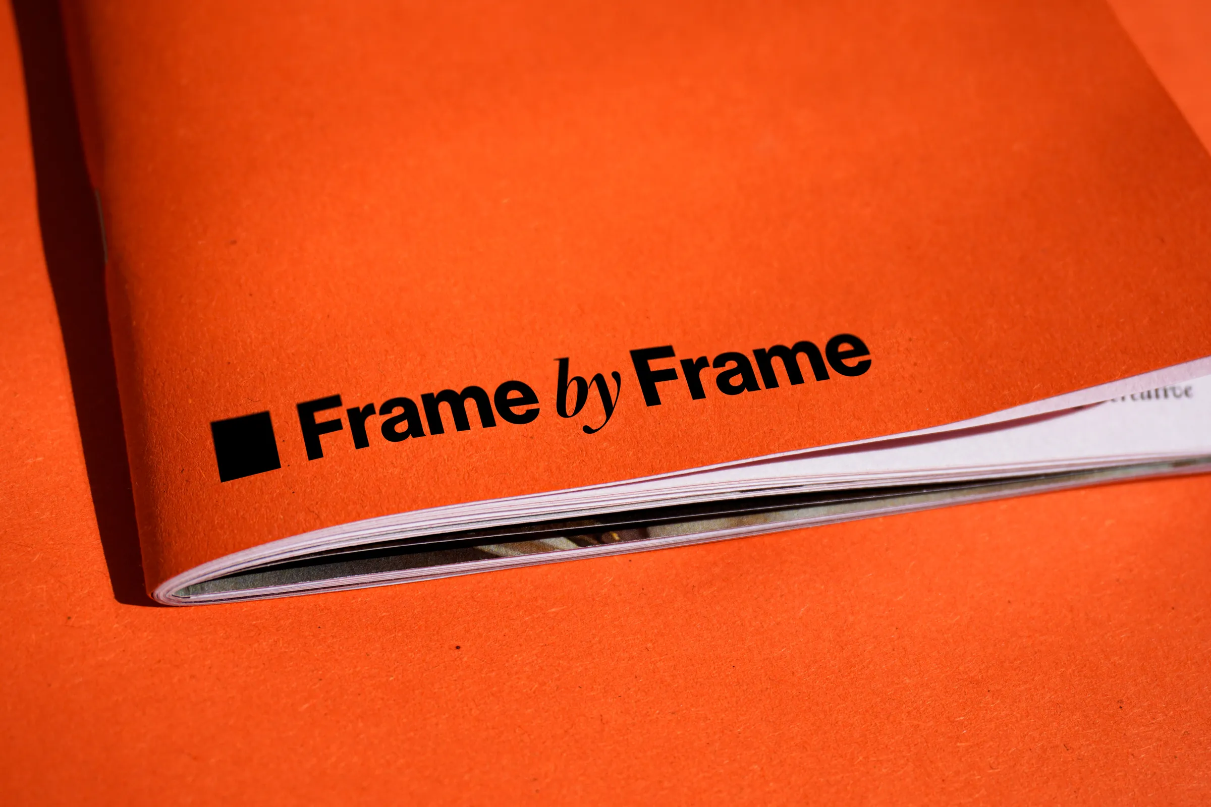 Livret imprimé Frame by Frame à couverture orange, logo en noir